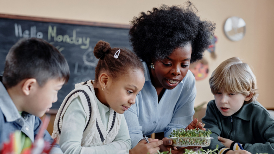 Teacher with three primary school students looking at watercress in classroom